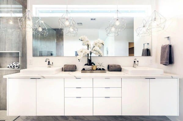 Modern double vanity with white cabinets, large mirror, and geometric pendant lights.