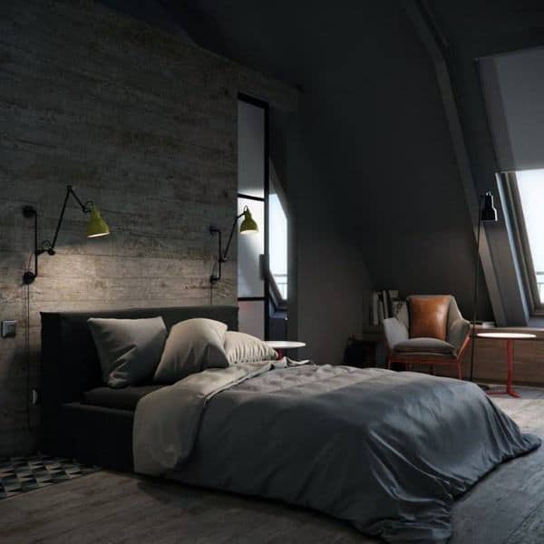 Cozy bedroom with a dark theme, featuring a bed with grey bedding, wall lamps, a leather chair, and a desk by the window