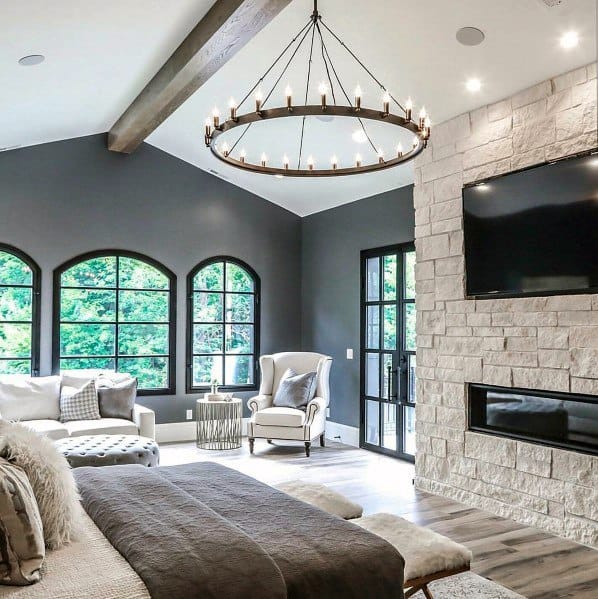 master bedroom with hardwood floors and stone fireplace