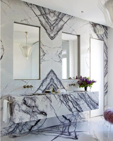 Marble bathroom vanity with geometric veining, wall-mounted faucets, and dual mirrors.