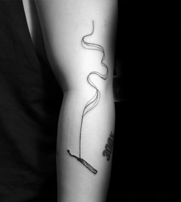 Minimalist tattoo of a burnt match with long, flowing smoke rising up the arm, symbolizing release, transience, or lingering impact.