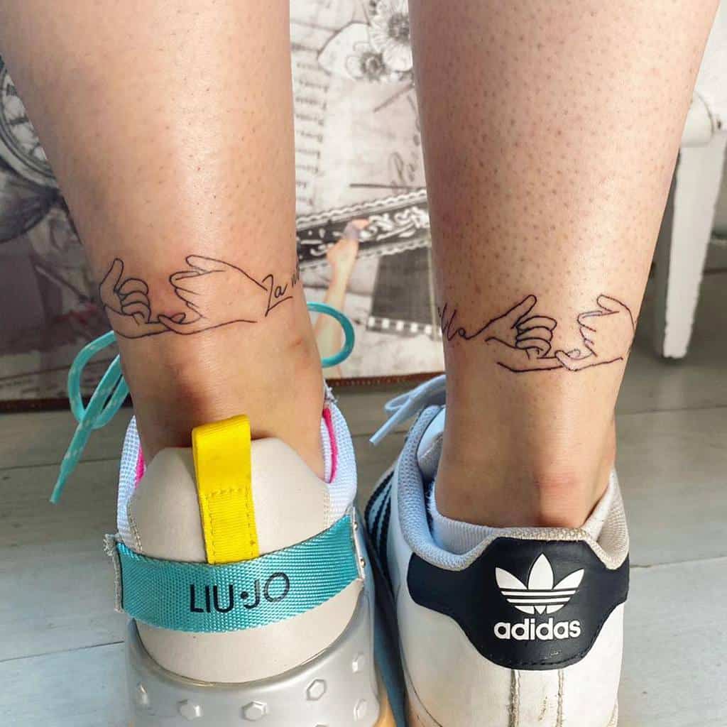 Matching pinky promise tattoos with minimalistic line art, placed on the backs of ankles, visible above stylish sneakers