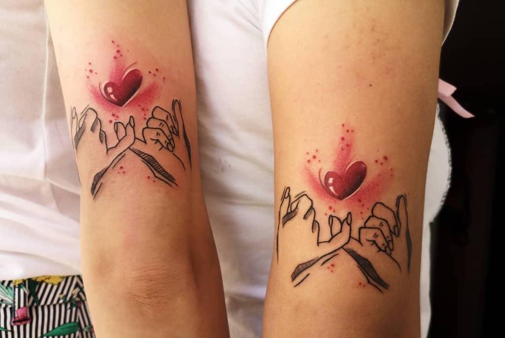 Matching pinky promise tattoos with black ink hands and a vibrant red heart above, surrounded by glowing red accents
