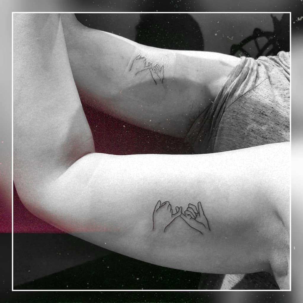 Two arms with matching line art tattoos of hands making pinky promises located on the inner sides of the arms