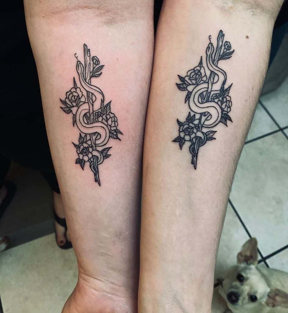 Matching sister tattoos featuring a snake wrapped around a staff with floral details, symbolizing strength, transformation, and unity