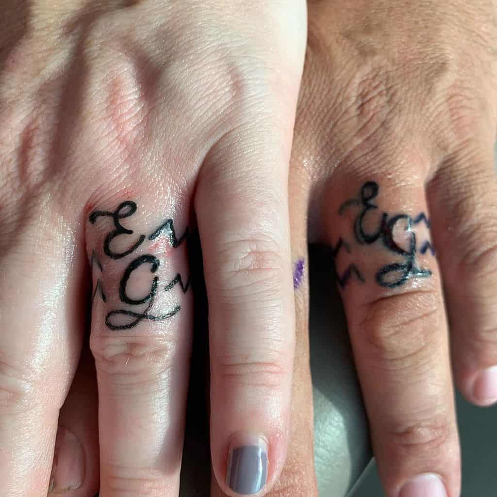Matching wedding ring tattoos featuring the initials "E" and "G" with elegant, flowing script, symbolizing a personal connection