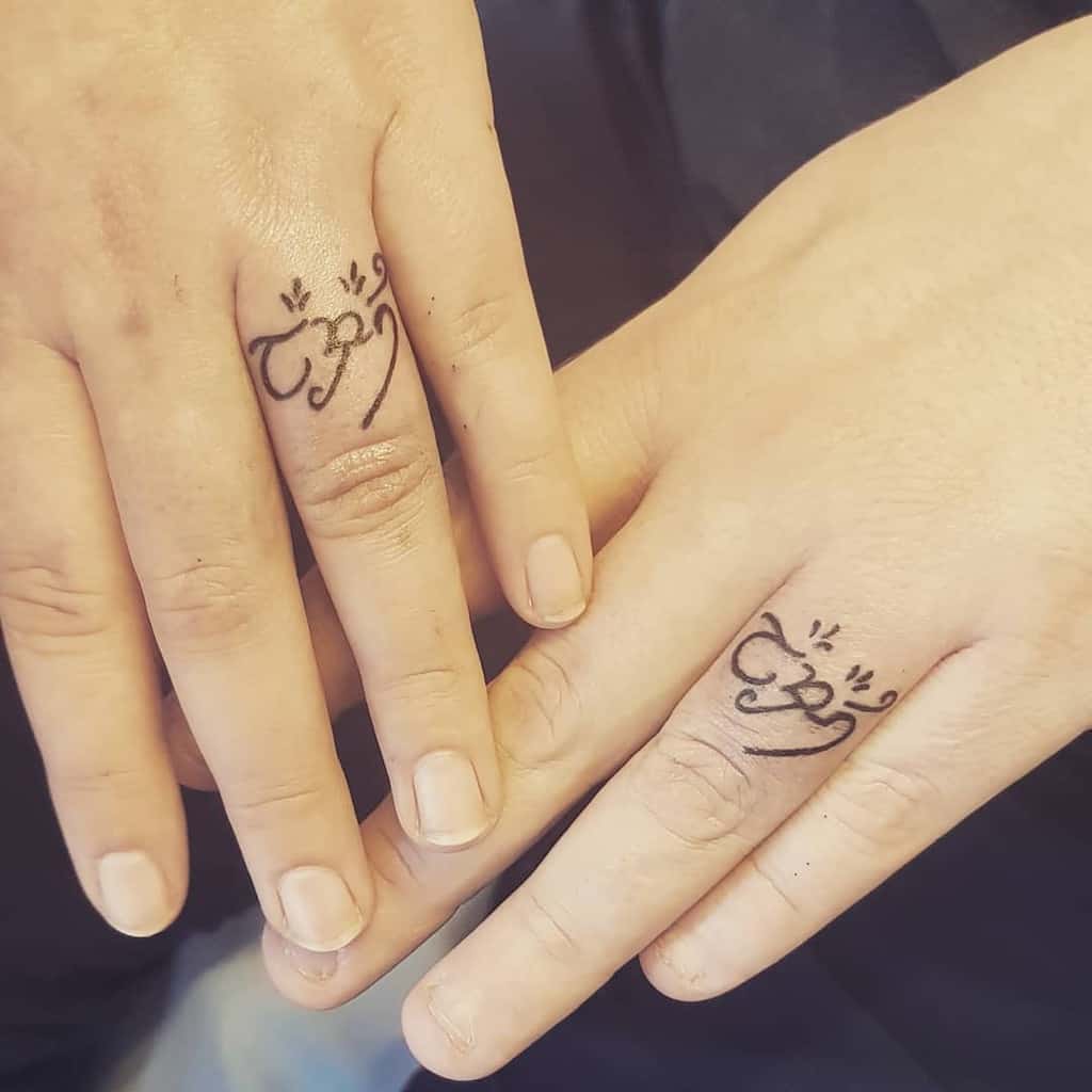 Matching wedding ring tattoos featuring elegant, flowing script, symbolizing a meaningful connection