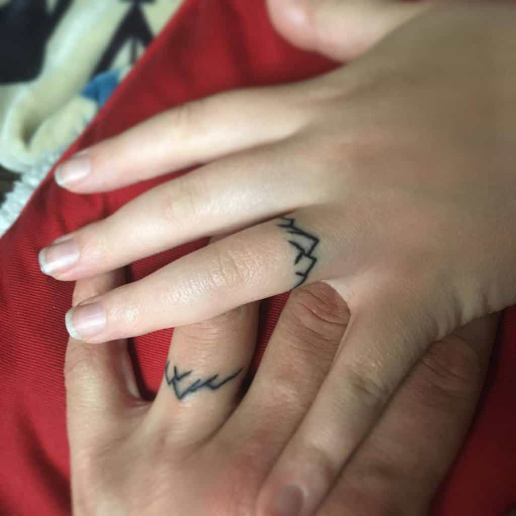 Matching wedding ring tattoos featuring mountain, symbolizing connection and shared bond