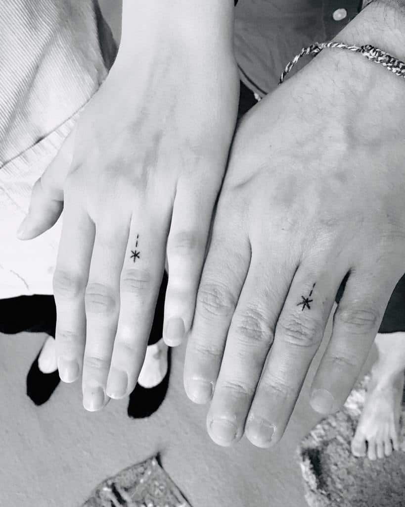 Matching minimalistic wedding ring tattoos of stars, with two dash line