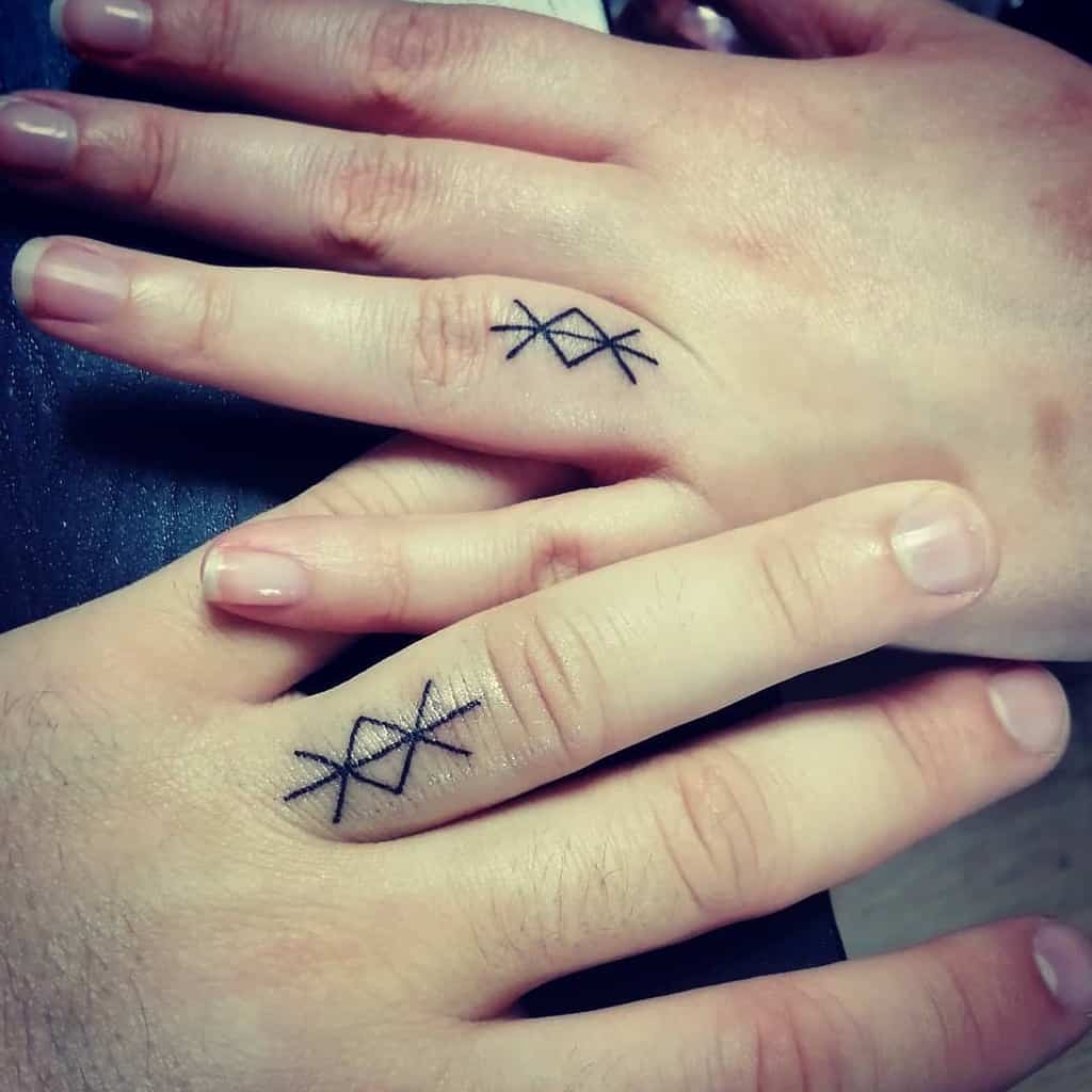 Matching geometric wedding ring tattoos featuring a pattern of intersecting lines with two 'X'
