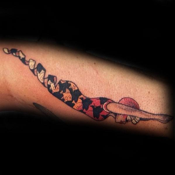 Colorful MC Escher-inspired tattoo of a diver formed from interlocking tessellated shapes, gradually transitioning along the arm.
