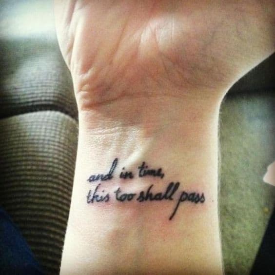 "And in time, this too shall pass" tattoo on the wrist in cursive font.