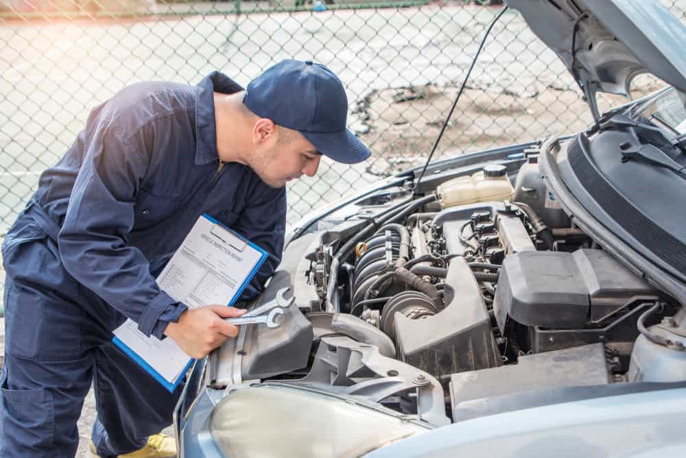 mechanic with scan tool diagnosing car in open hood