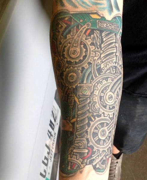 Arm tattoo featuring intricate gears and mechanical components in black and grey ink