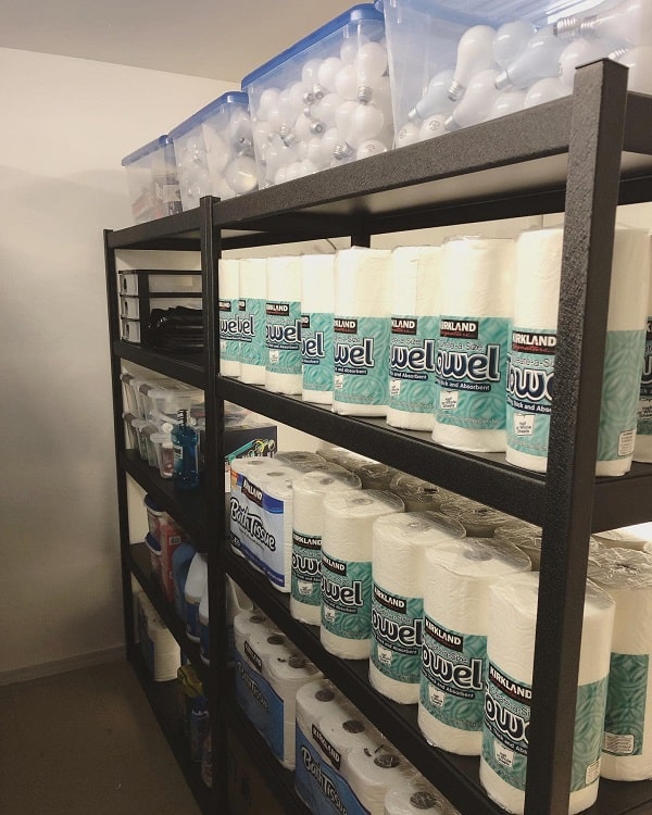 Basement shelves storing paper towels, cleaning supplies, and light bulbs in labeled bins.