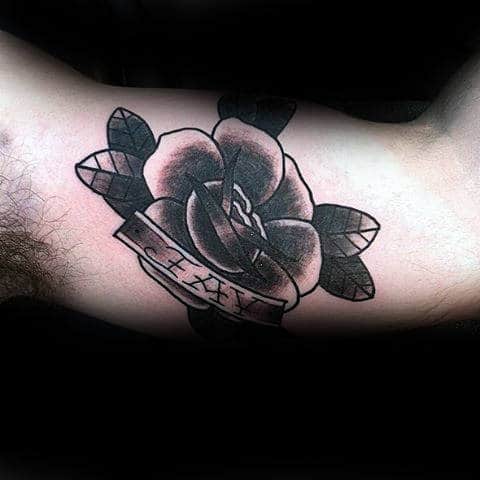Tattoo of a rose with leaves on an arm, featuring a banner labeled "JAY"