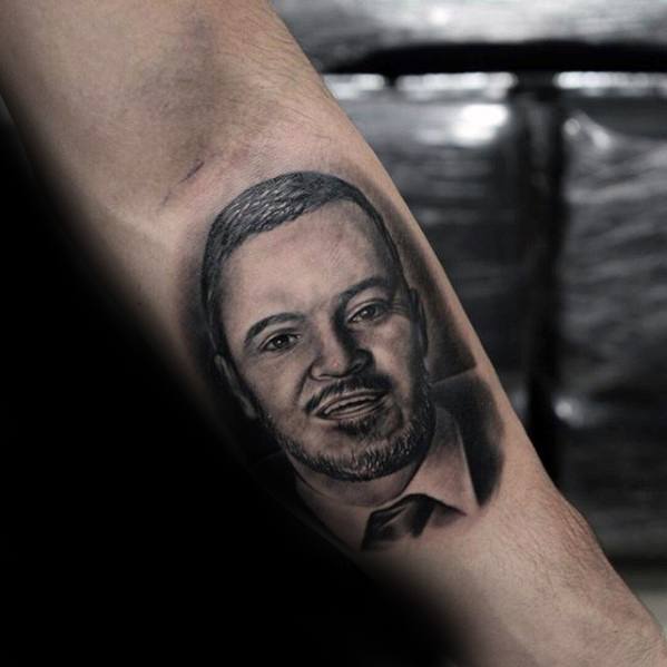 Tattoo of a man's face with a beard on someone's inner forearm