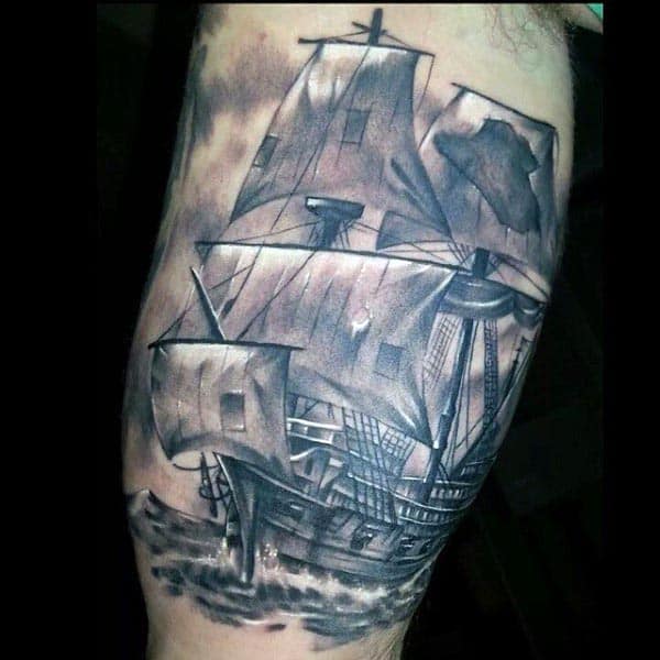 Black and grey tattoo of a detailed pirate ship with tattered sails, sailing through rough waters, creating a dramatic and realistic design
