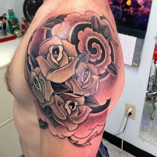 Tattoo of roses and leaves on a man's upper arm and shoulder