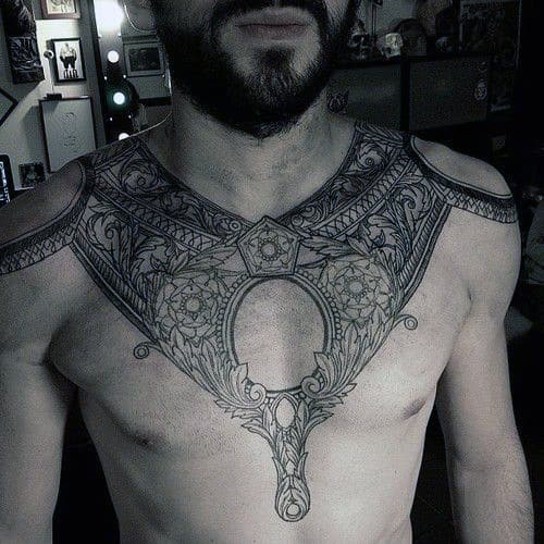 Man with an intricate chest and shoulder tattoo in a dimly lit room