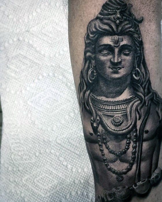 Forearm tattoo of Lord Shiva with defined features, adorned with rudraksha beads, crescent moon, and snake, rendered in bold black shading.