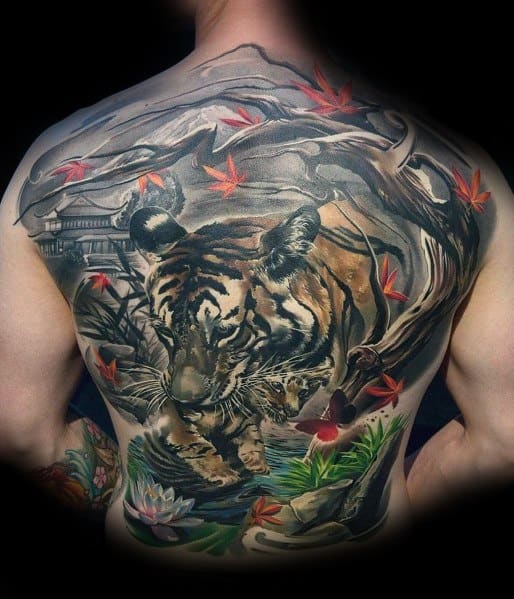 Large full-back tattoo featuring a realistic tiger prowling through a Japanese-inspired landscape with maple leaves, a temple, and a flowing river.