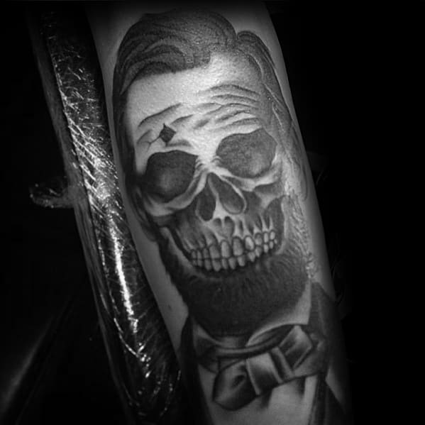 Tattoo of a man with a skull face in Abraham Lincoln's historical suit