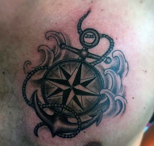 Tattoo of a compass rose entangled with an anchor and surrounded by waves on a chest