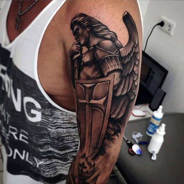 A tattoo of an armored angel with a sword and shield on a person's upper arm