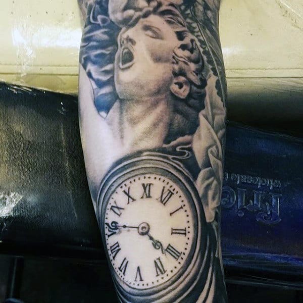 Tattoo of a clock with Roman numerals and a classical statue-like face on an arm
