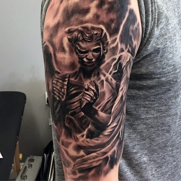 Tattoo of an angel with dark shadows on a person's upper arm