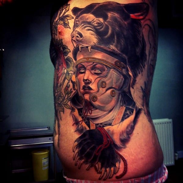 Tattoo of a bear, a face, and mechanical elements on a person's side