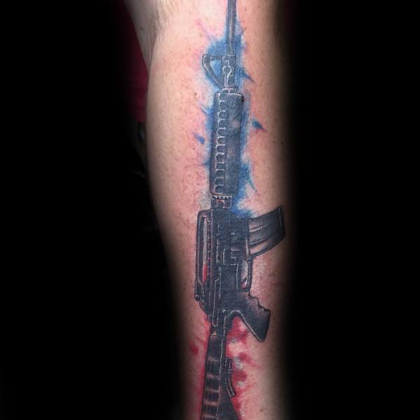 Black and grey AR-15 tattoo with red and blue watercolor-style background, symbolizing patriotism, strength, and firearm appreciation.