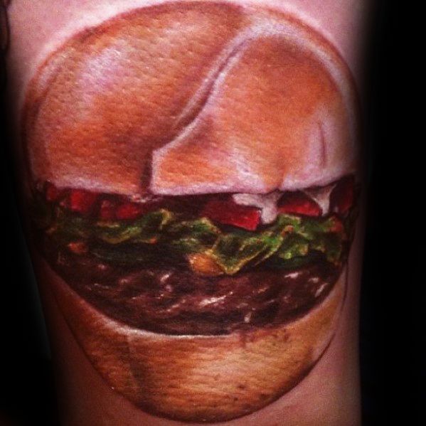 A lifelike cheeseburger tattoo with lettuce and tomato adorns the skin