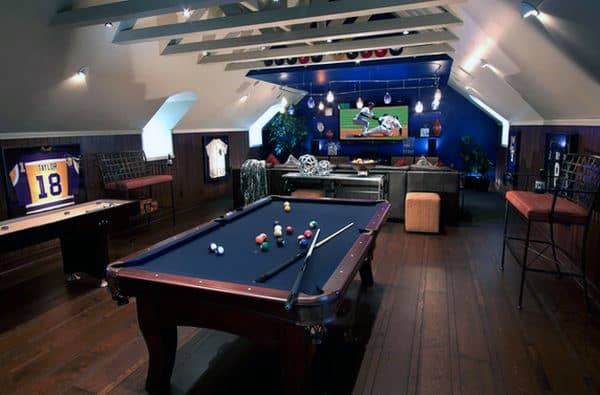 A game room with a pool table, sports jerseys, bar seating, and a TV showing a football game