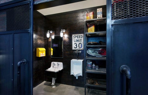 Industrial-style bathroom with a sink, urinal, metal shelving, and a "Speed Limit 30" sign on the dark wood wall
