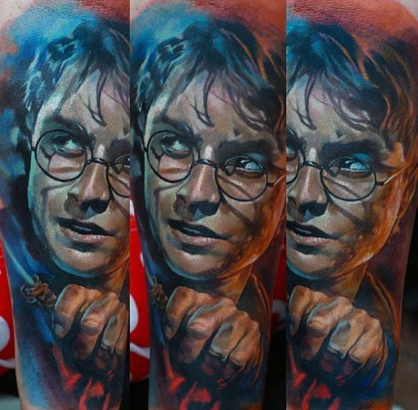 Vivid color tattoo of a character with glasses and a wand, depicted in a dramatic pose on the forearm