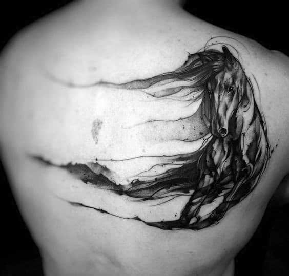 Artistic black ink tattoo of a flowing horse in watercolor style, placed on the upper back with abstract brush stroke elements