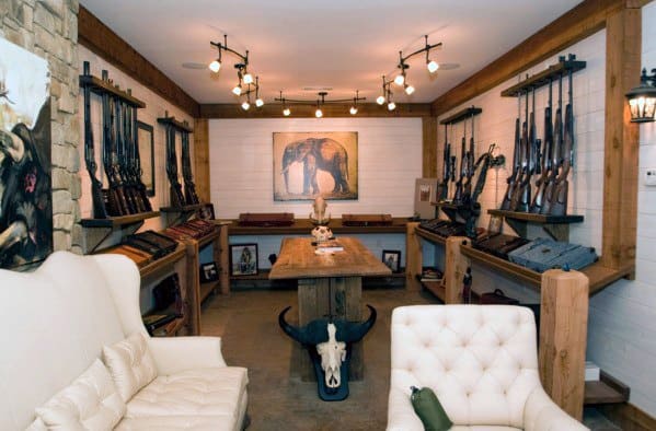 A rustic room displaying guns on the walls and a central table, with seating and decor featuring animal motifs
