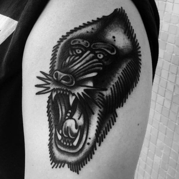 Blackwork baboon tattoo with bold shading, fierce open-mouthed expression, and extra eyes, creating a surreal and striking upper arm design.