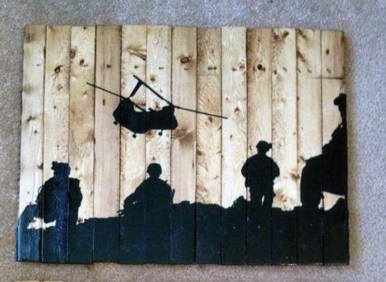 Wooden wall art featuring black military silhouettes and a helicopter design.