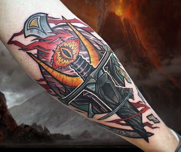 An arm tattoo features the Eye of Sauron aflame, paired with a gleaming sword against a backdrop of stormy skies and towering mountains