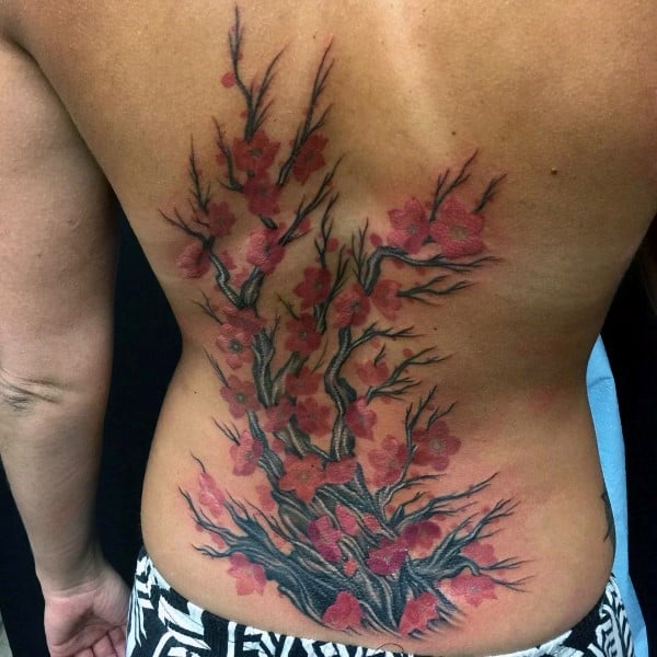 Large back tattoo featuring a detailed cherry blossom tree with dark twisted branches and vibrant red flowers spreading across the spine
