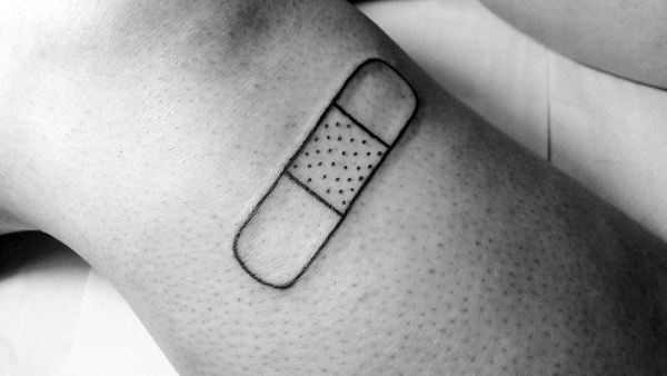 Minimal Band-Aid tattoo outlined in black ink with dotted detail, offering a clean and simple design on the leg.