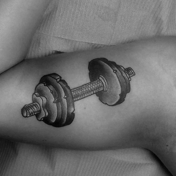 Detailed dumbbell tattoo on bicep with realistic shading and texture, symbolizing strength, progress, and commitment to fitness.