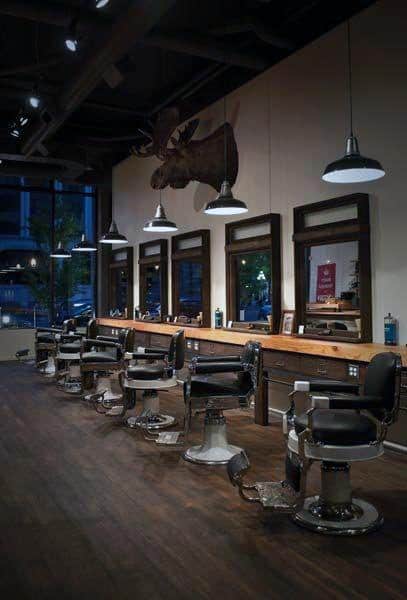 Barbershop with dark wood floors, leather chairs, and a mounted moose head decor.
