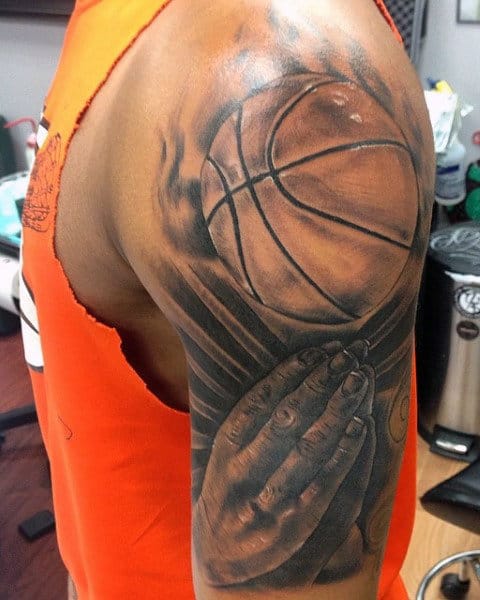 Arm tattoo depicting hands gripping a basketball, with the hands appearing to wear an orange sleeveless shirt