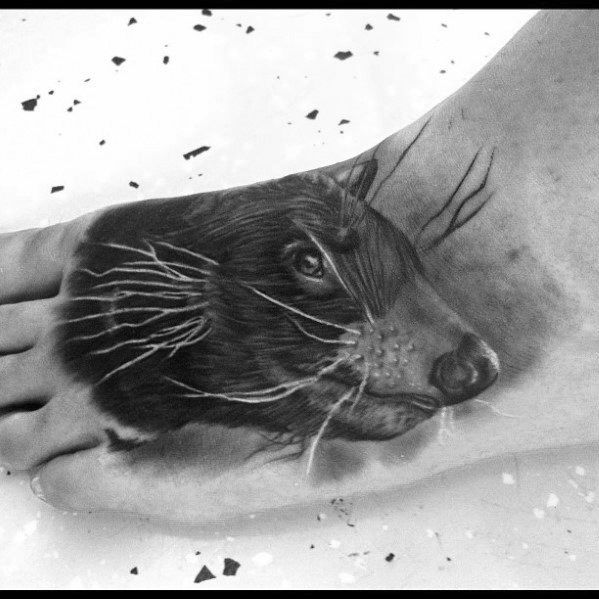 Hyper-realistic black and grey beaver tattoo on the foot, featuring lifelike fur, whiskers, and a focused gaze with fine detail.