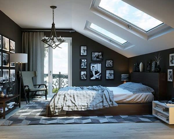 Modern attic bedroom with skylights, dark walls, gallery wall art, and a cozy wooden bed.