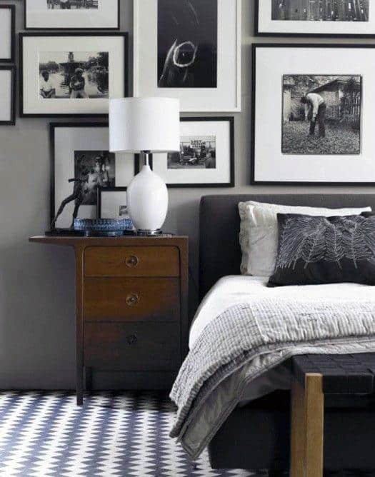 Stylish bedroom with black and white gallery wall, wooden nightstand, and geometric rug.